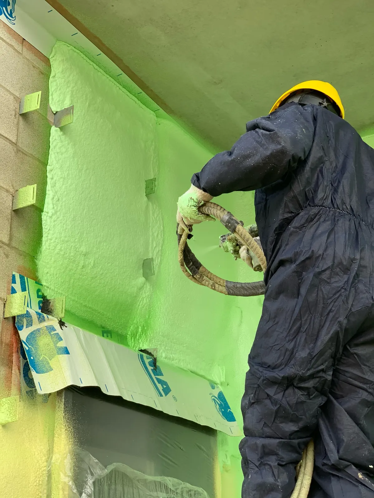 Technician spraying foam insulation into a wall cavity