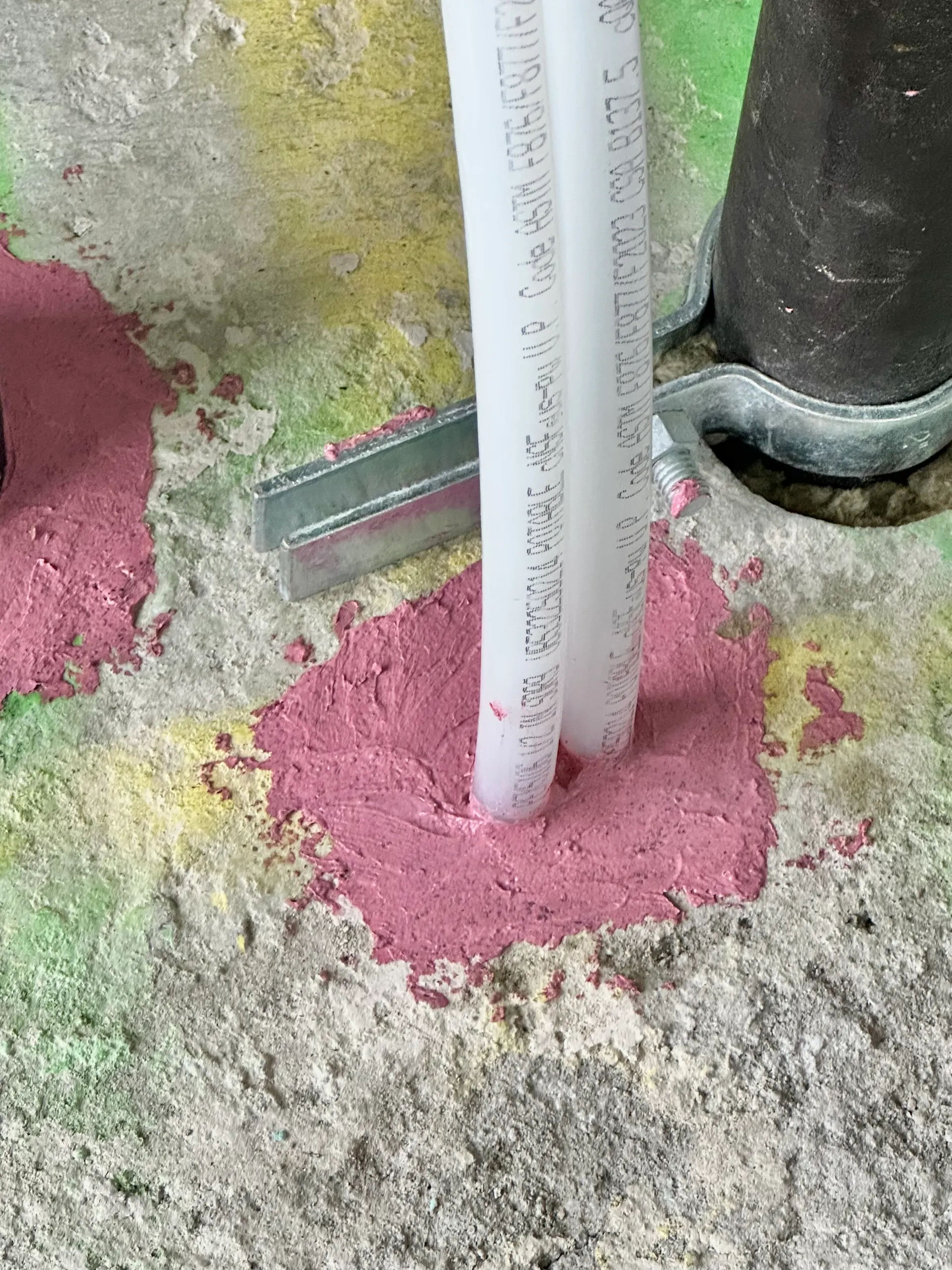 Red firestop sealant at plastic pipe penetrations through a concrete slab