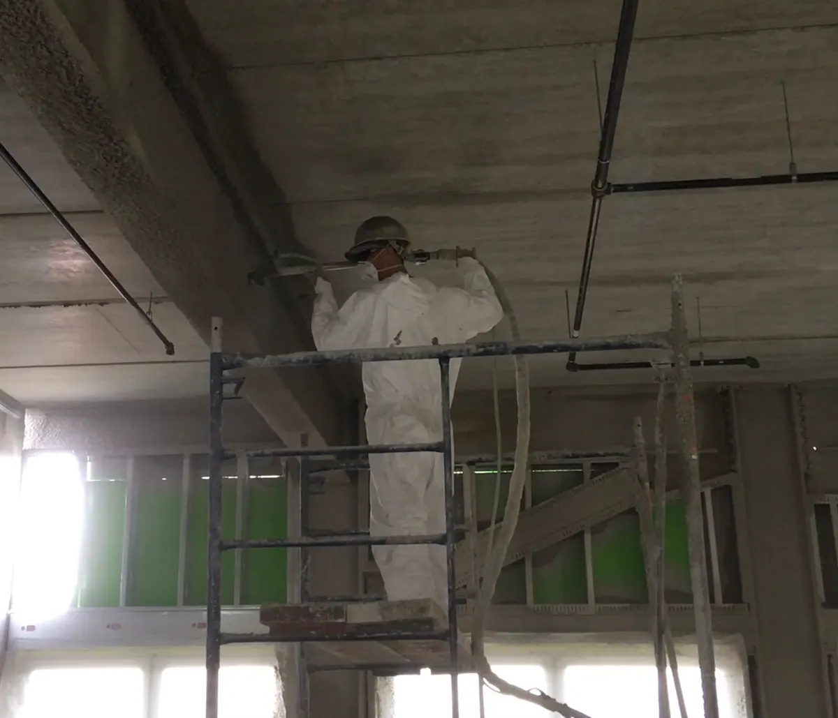 Applicator spraying fire-protection material overhead