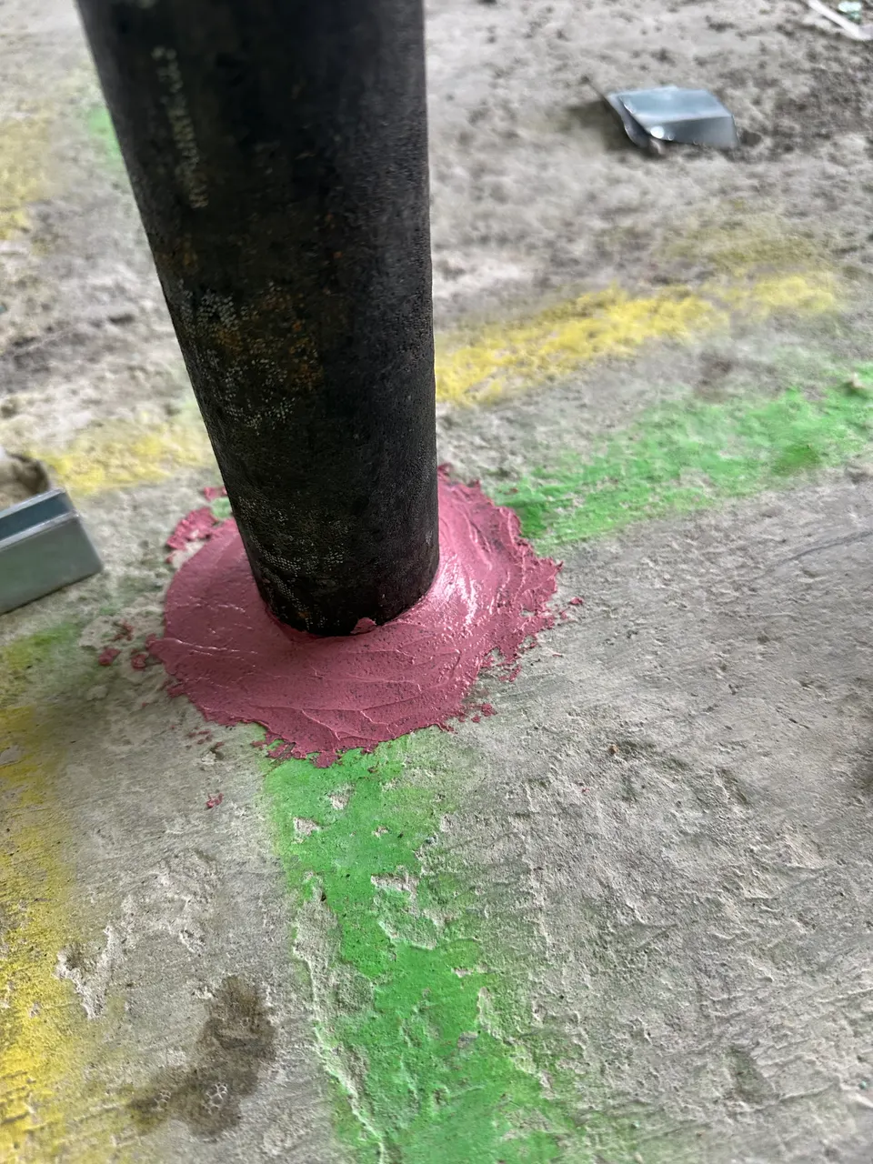 Red firestop sealant around a pipe penetration through a concrete floor