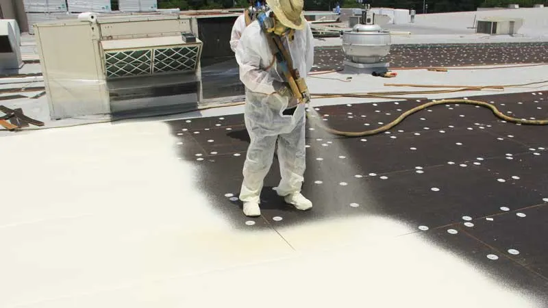 Applicator spraying polyurethane foam on a flat roof