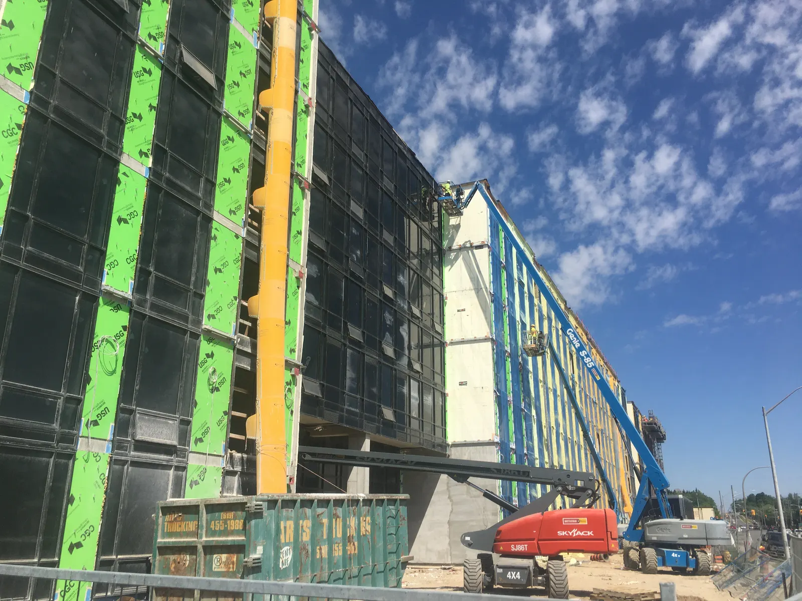 Crew installing an exterior air and vapour barrier from an elevated work platform