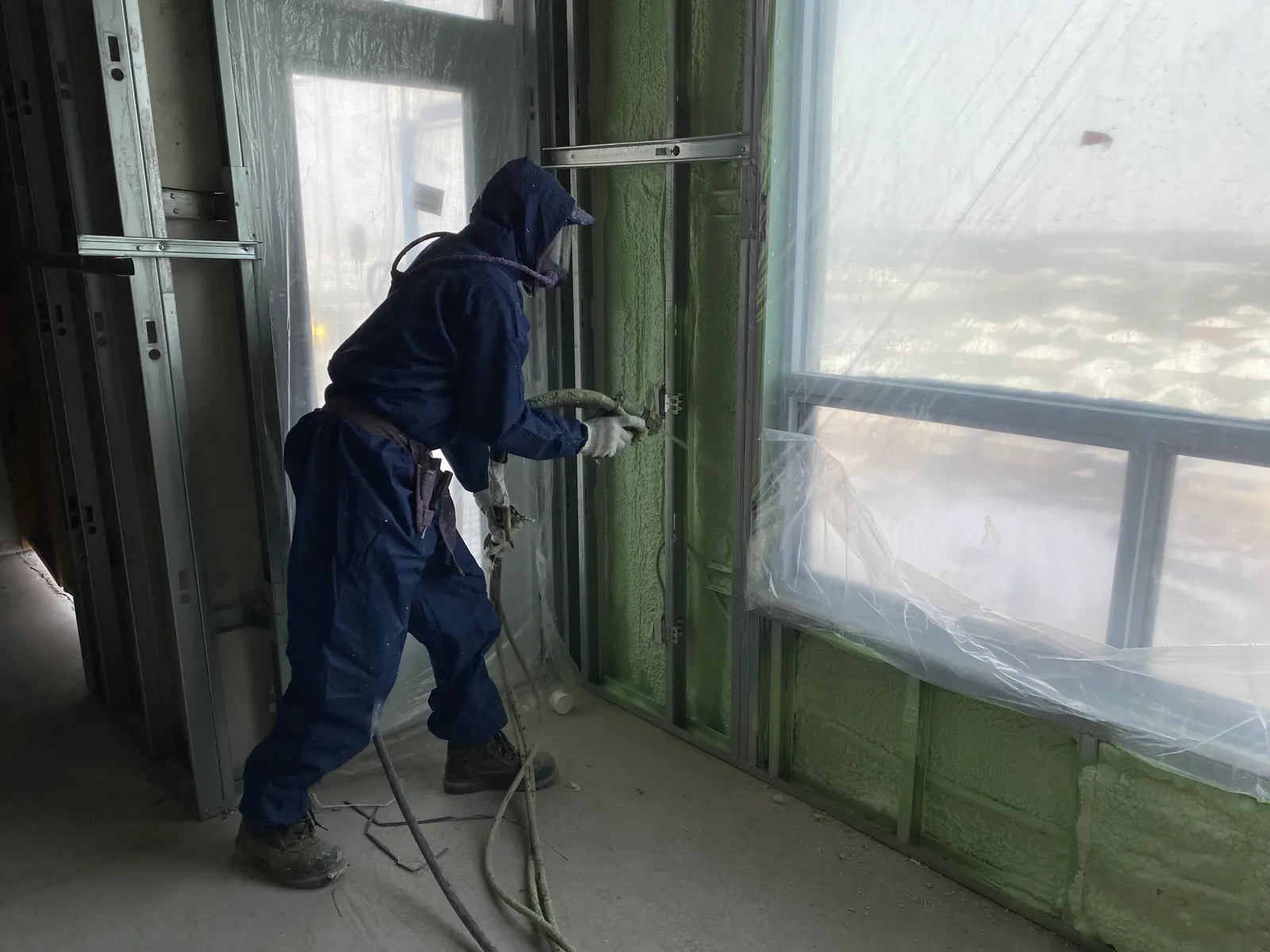 Technician applying spray foam around an interior window opening