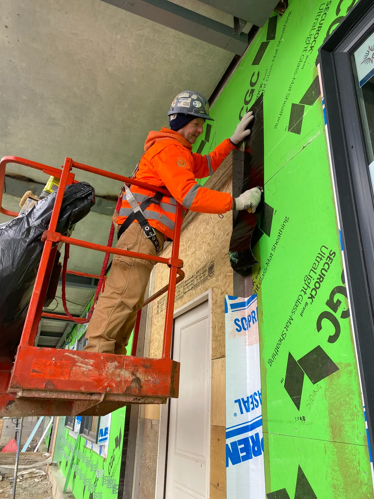 Technician applying an exterior air and vapour barrier around a window