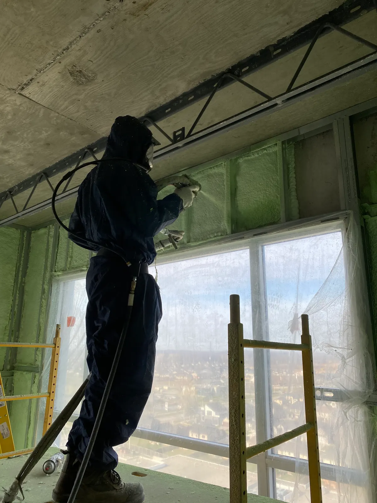 Technician applying spray foam insulation above an interior window