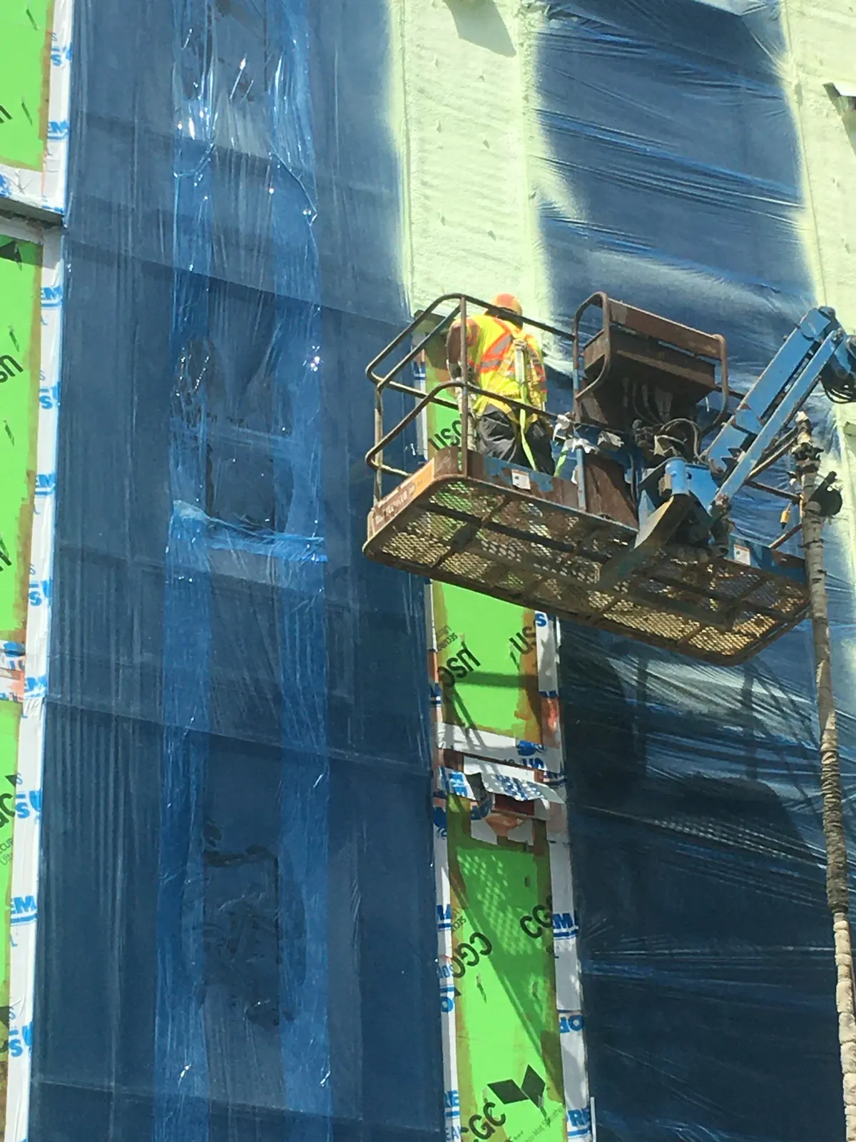 Crew applying blue air and vapour barrier from a lift