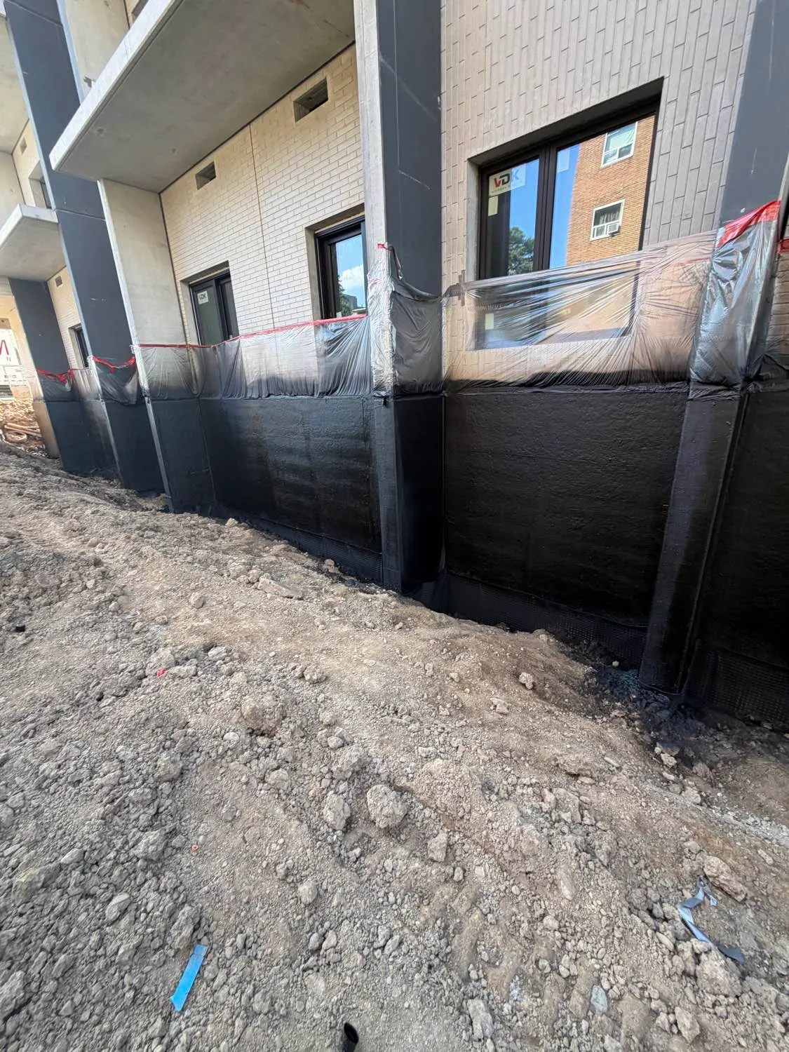 Below-grade waterproofing membrane on a foundation wall with the excavation still open
